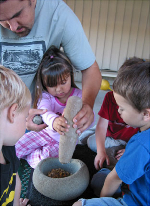 Tony Johnson teaches pre-schoolers how to traditionally process acorns using a mortar and pestle